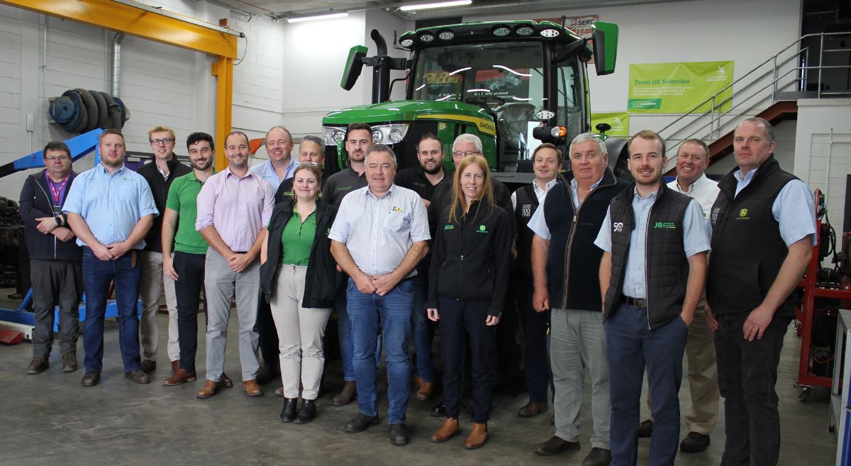 Group of 198 men and women in front of a John Deere Tractor in SERC  vehicle workshop